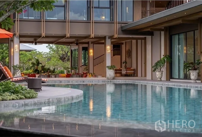 Detached House for rent in Bang Kapi, Bangkok - Curved community swimming pool surrounded by greenery and sun loungers