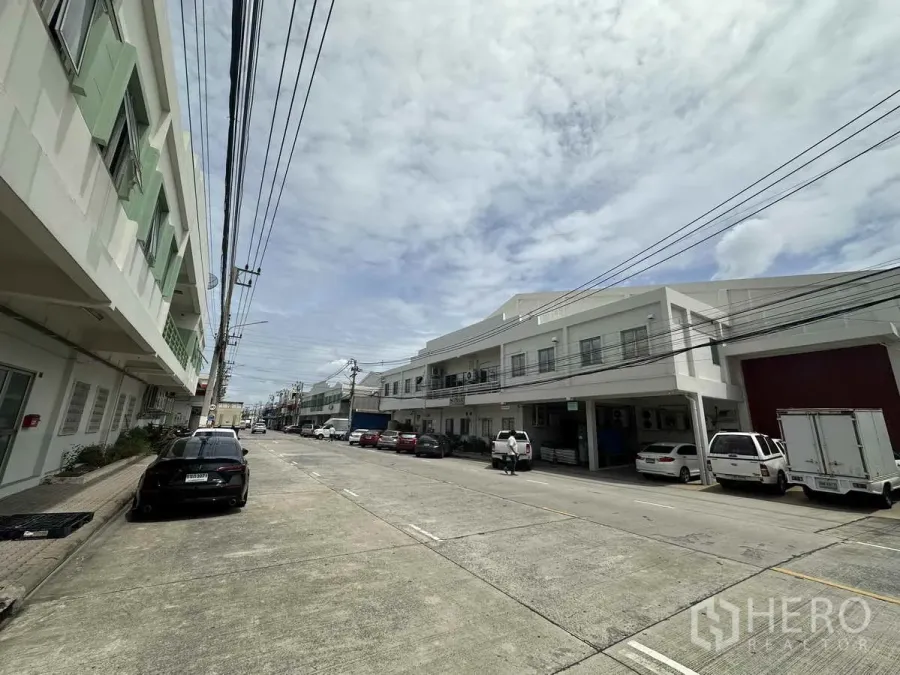 Factory for rent in Khlong Luang, Pathum Thani - Street view of factory row with parking and a 15 m wide access road in the industrial estate.