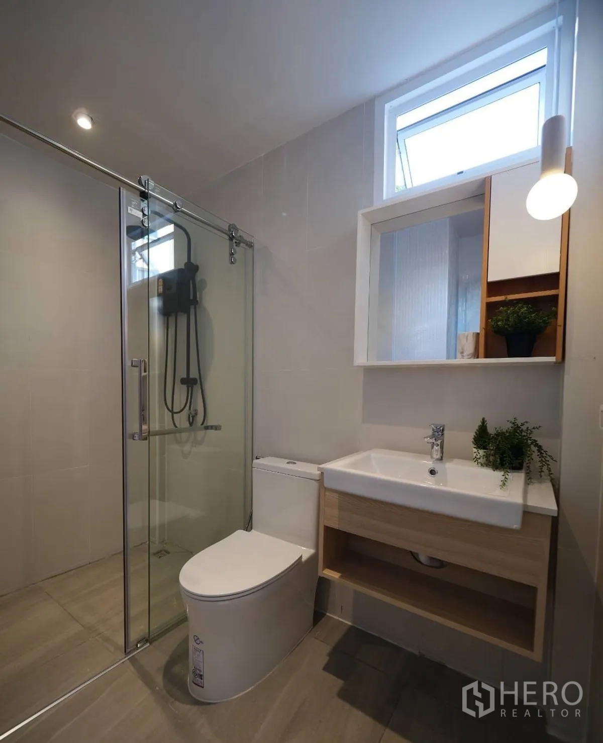 Townhouse for rent or sale in Watthana, Bangkok - Modern bathroom with glass shower enclosure, vanity and window.
