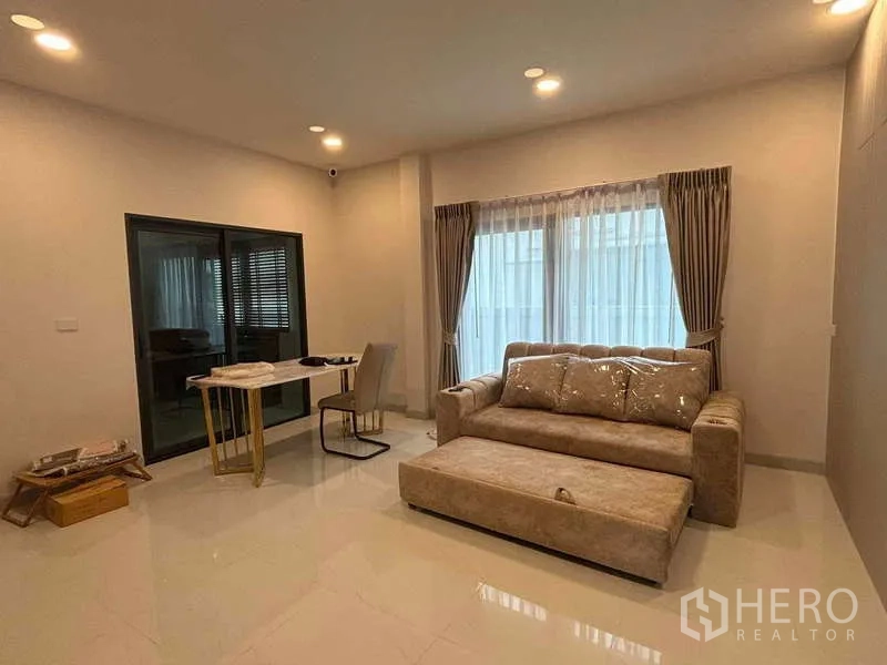 Detached House for rent in Mueang Nonthaburi, Nonthaburi - Cozy living area with sofa, small dining set and wide window dressed with curtains.