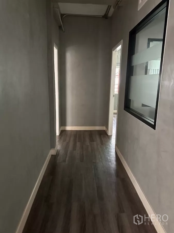 Shophouse for sale in Watthana, Bangkok - Grey hallway with internal glass window and doors to small offices.