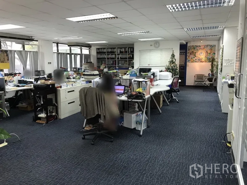 Office Space for rent in Khlong Toei, Bangkok - Large carpeted office area with desks, storage cabinets, wide windows and bright ceiling lights.