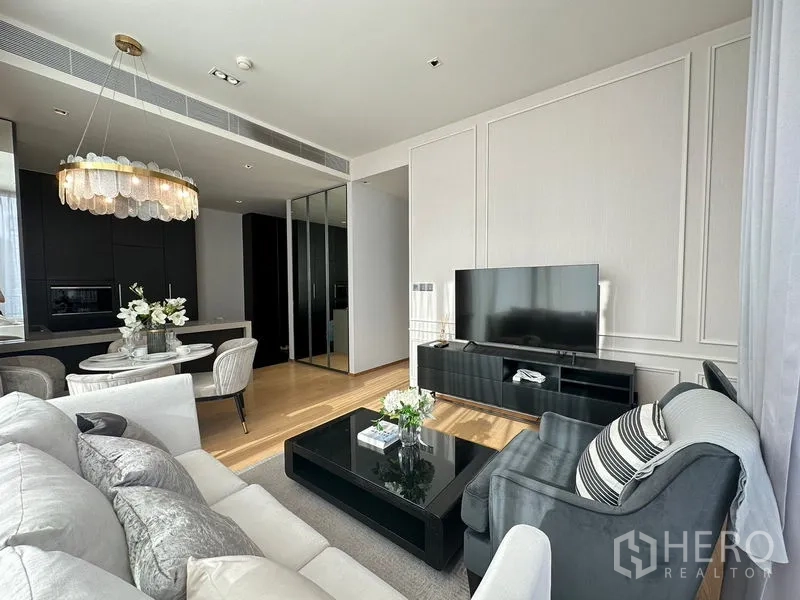 Condominium for rent in Pathum Wan, Bangkok - Bright living room with sofa set, TV console and a round dining area under a chandelier.