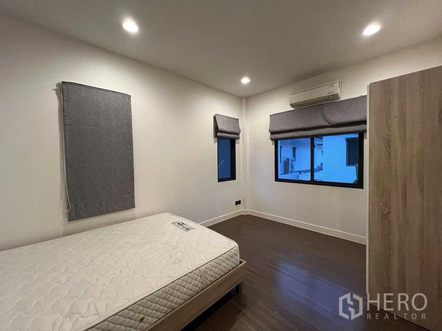 Detached House for rent or sale in Bang Kapi, Bangkok - Bedroom with twin windows, bed and wood flooring.