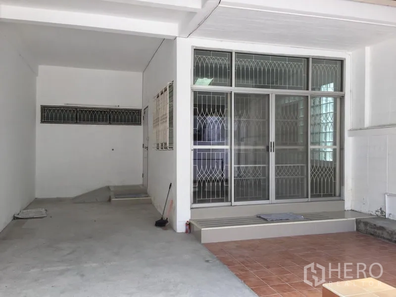Townhouse for rent in Phra Khanong, Bangkok - Covered carport and tiled entry with sliding glass door and security grilles.