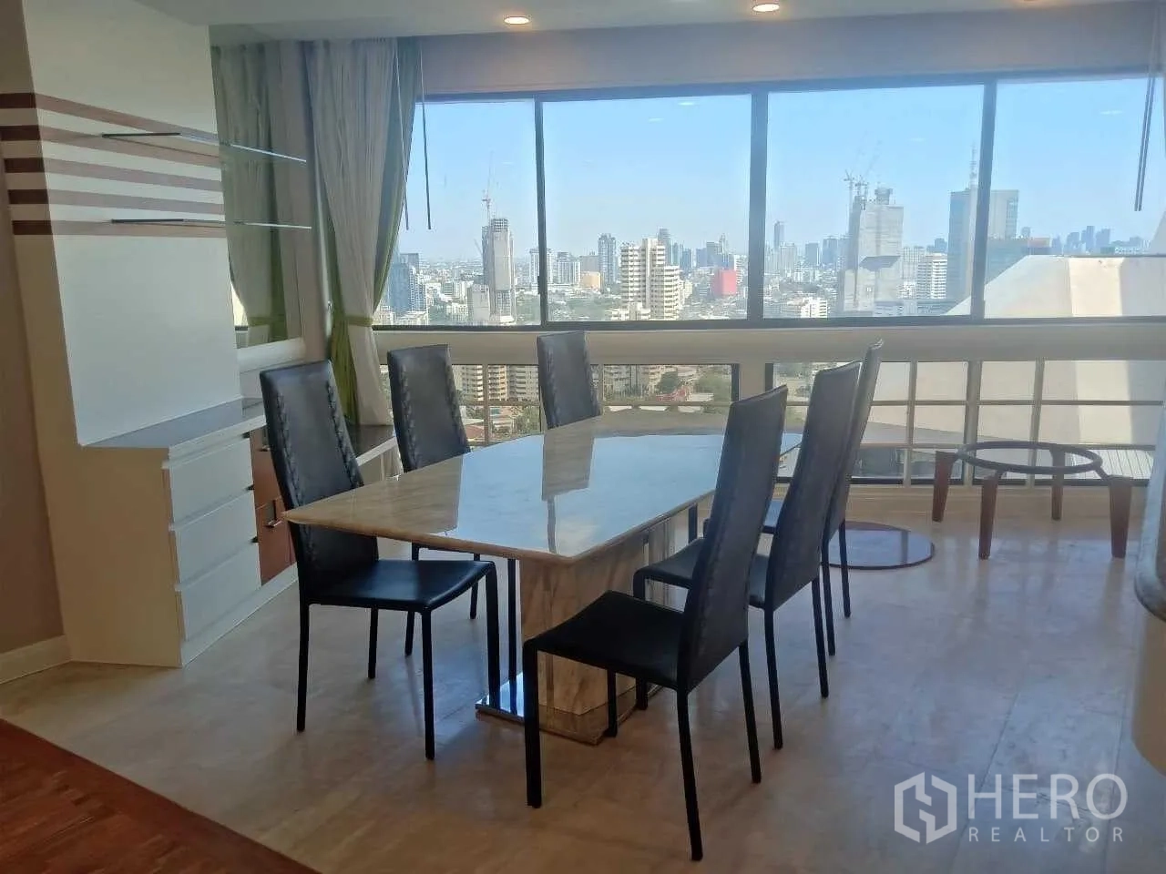 Condominium for rent in Khlong Toei, Bangkok - Dining area with marble table, six chairs and wide Bangkok skyline views.