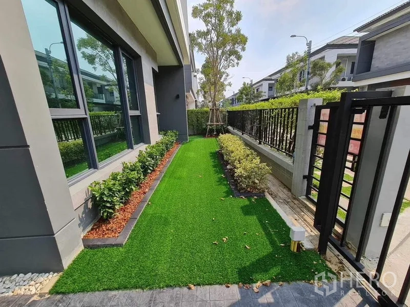 Detached House for rent or sale in Bang Phli, Samut Prakan - Front garden with artificial lawn, hedge border and black gate.