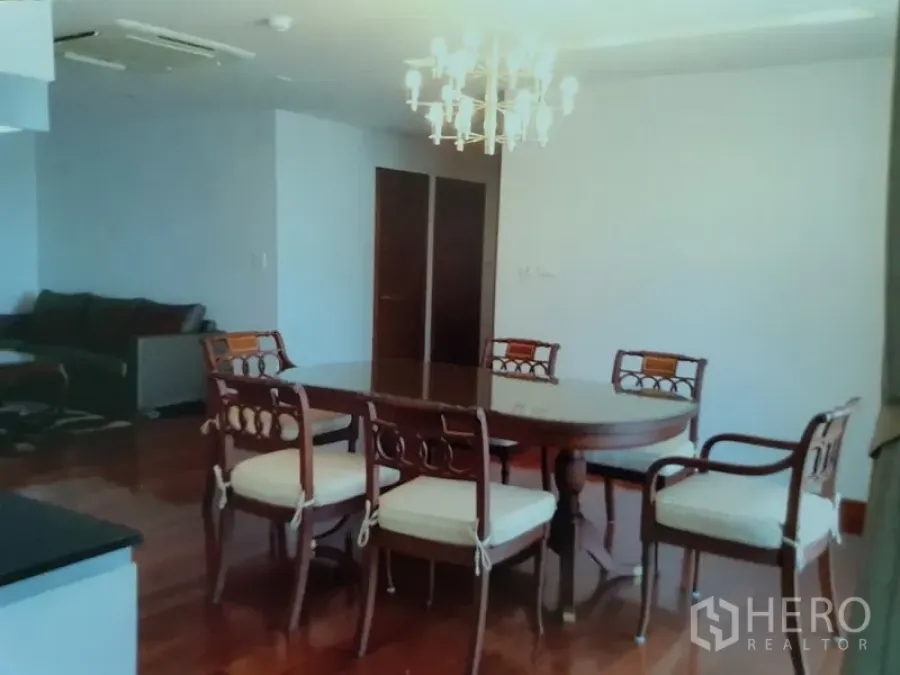 Condominium for rent in Watthana, Bangkok - Bright dining area with an oval wooden table, chandelier and hardwood floors beside the living room.
