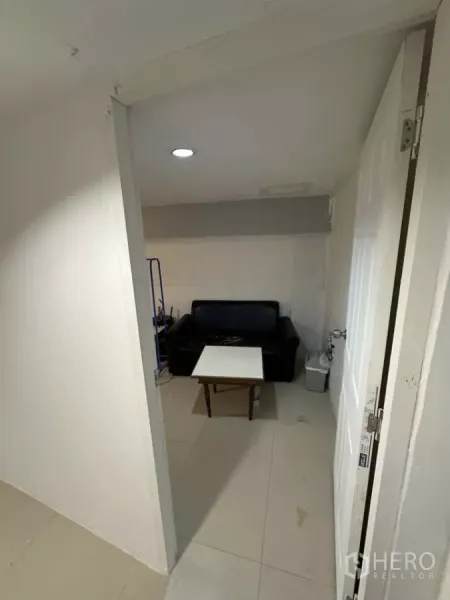 Retail Space for rent - Small back room with a black sofa and table under recessed ceiling lighting.