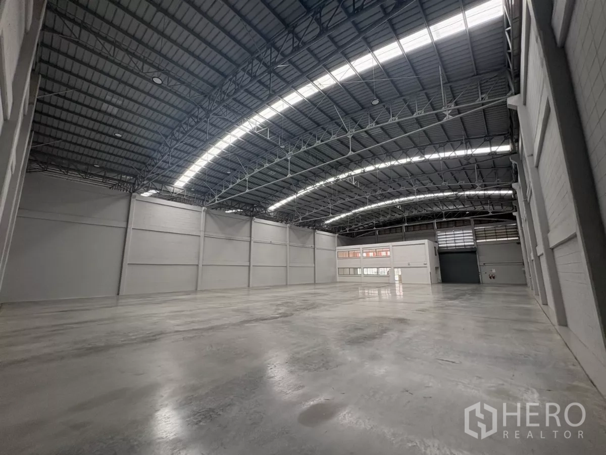 Factory for rent in Bang Phli, Samut Prakan - Expansive warehouse hall with skylights, polished concrete and dual roller doors.