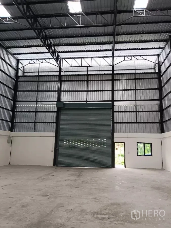 Warehouse for rent in Khlong Toei, Bangkok - Interior view facing the roller shutter with side access door and windows.