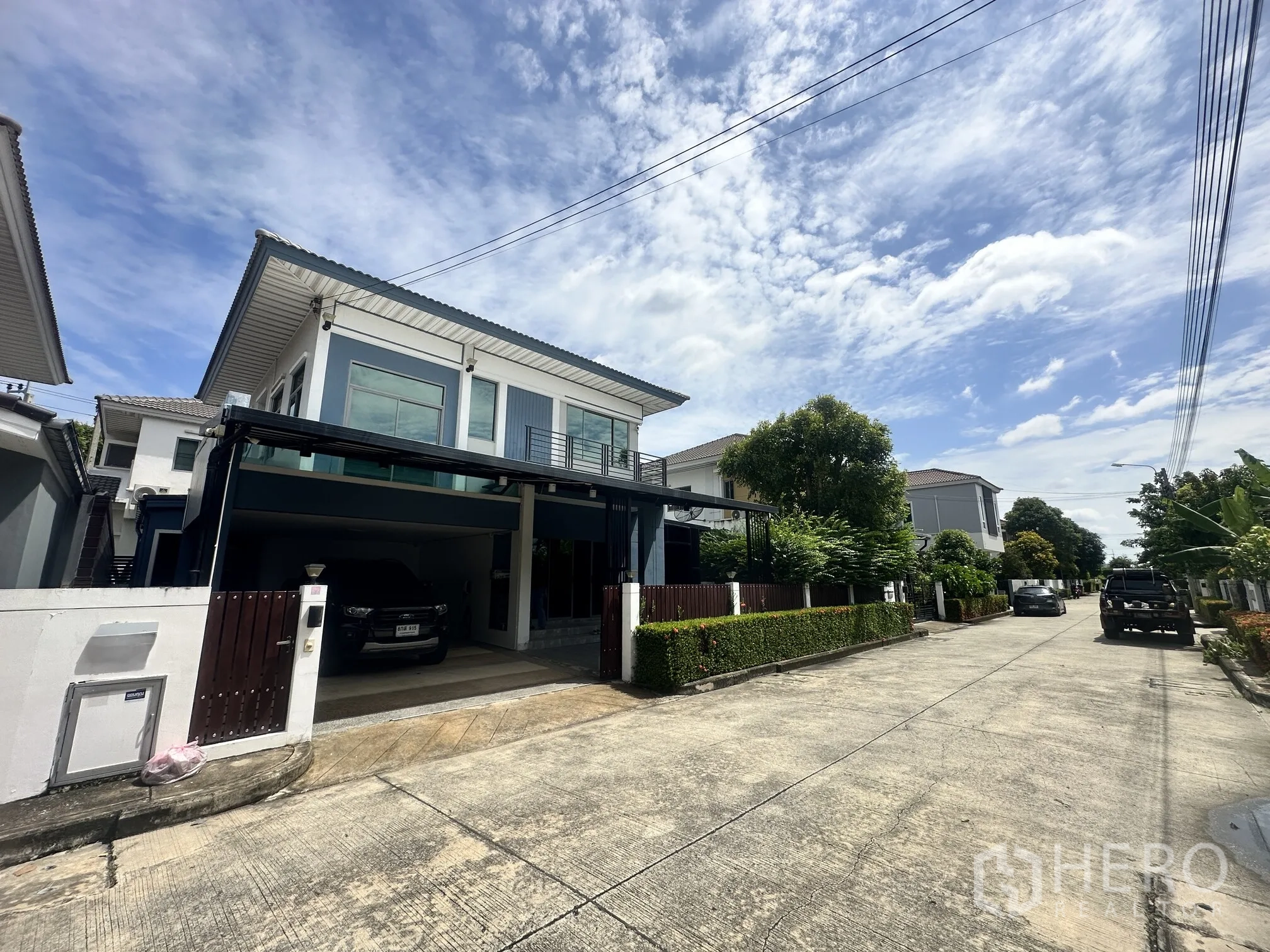 独栋房屋 for sale in Pak Kret, Nonthaburi - 两层独栋别墅外观，带有顶棚车位与安静社区道路。