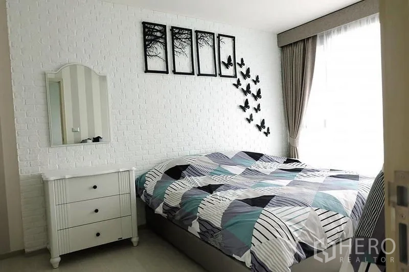 Condominium for rent in Khlong Toei, Bangkok - Bedroom angle showing dresser, wall art and floor-to-ceiling curtains next to the bed.