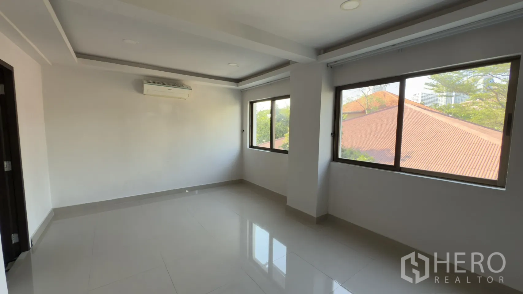 Townhouse for rent in Watthana, Bangkok - Corner room with multiple windows and a wall-mounted air conditioner providing abundant natural light.