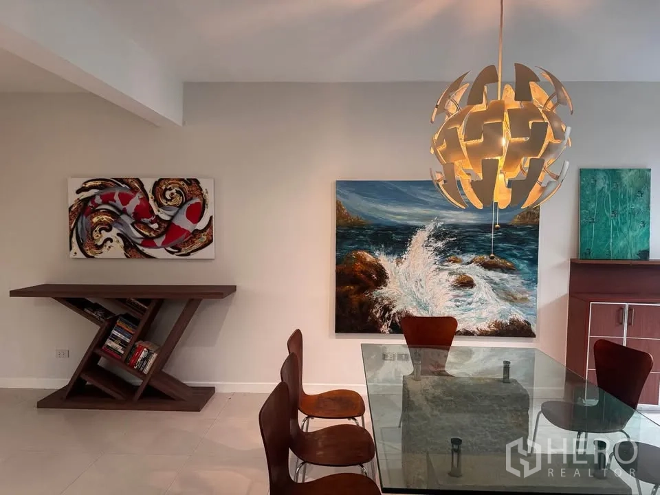 Townhouse for rent in Huai Khwang, Bangkok - Dining area with glass table, designer pendant light and wall art.