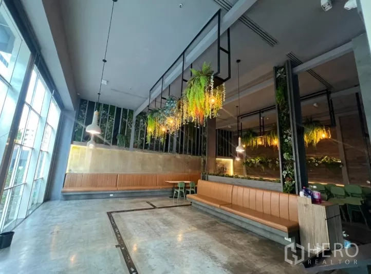 Retail Space for rent - Spacious restaurant hall with concrete floors, benches and hanging plants.