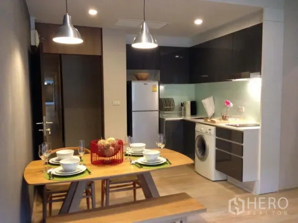 Condominium for rent in Watthana, Bangkok - Open-plan kitchen and dining with glossy cabinets, fridge, washing machine and pendant lighting.