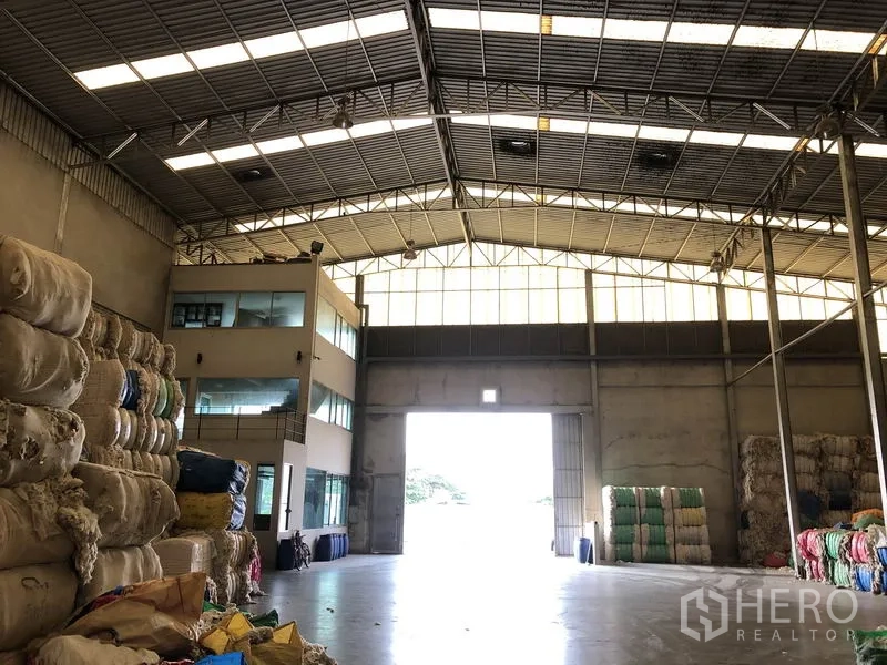 Factory for rent in Bang Bua Thong, Nonthaburi - Warehouse entrance with tall roller door and attached glass-fronted office block.