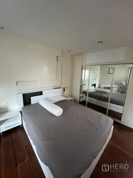 Condominium for rent - Bright master bedroom with hardwood floors, white headboard and mirrored wardrobe.