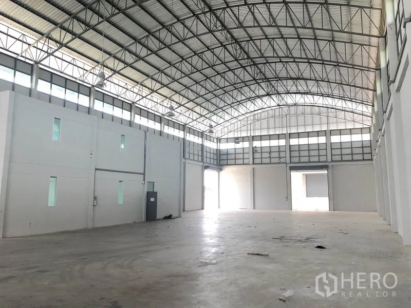 Factory for rent in Lam Luk Ka, Pathum Thani - Bright clear‑span production hall with two roller shutters, steel truss roof and white walls.