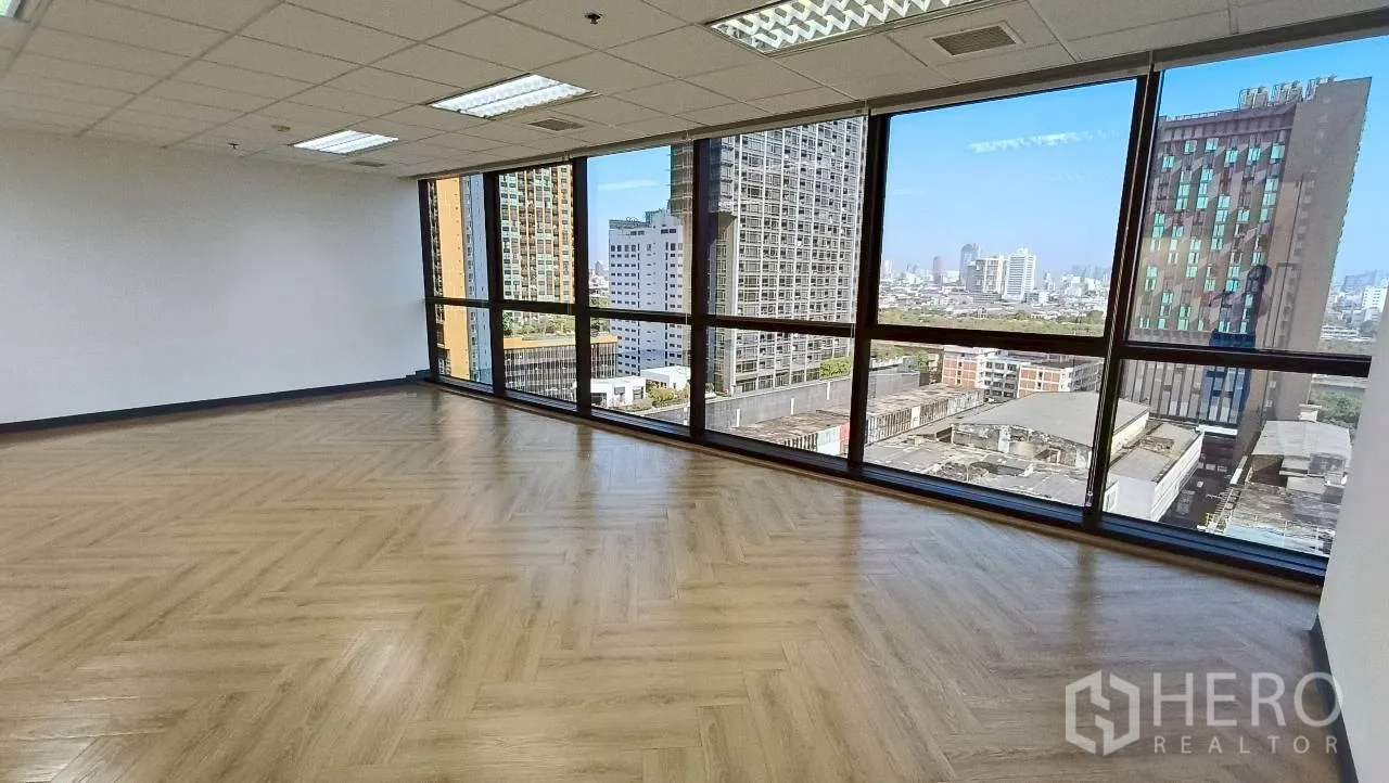 Office Space for rent in Ratchathewi, Bangkok - Open office area with long window wall overlooking high-rise buildings and wood floors.