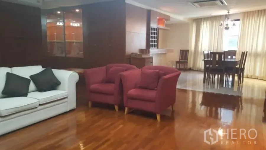 Condominium for rent in Khlong Toei, Bangkok - Open-plan living and dining room with polished wooden floors and sofa set.
