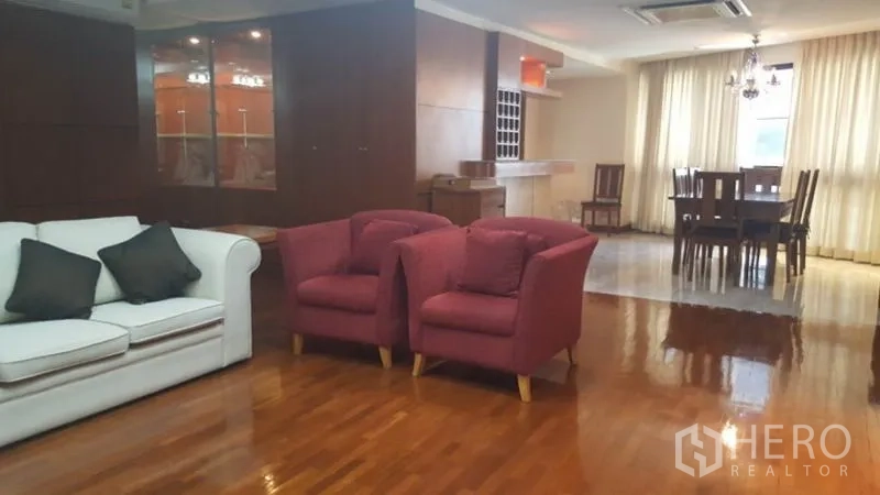Condominium for rent in Khlong Toei, Bangkok - Open-plan living and dining room with polished wooden floors and sofa set.