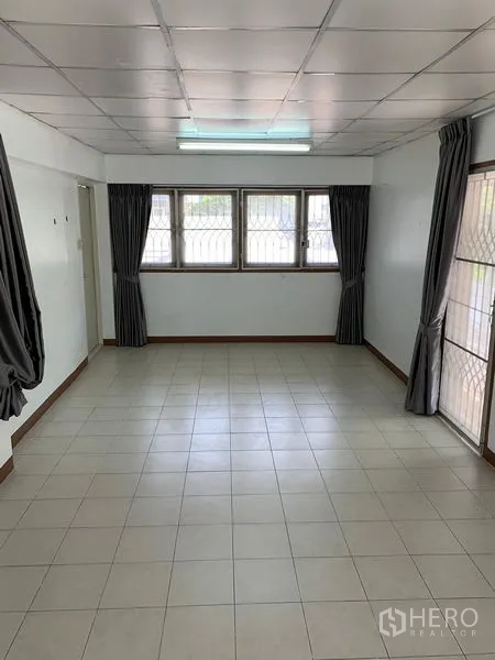 Office Space for rent in Chatuchak, Bangkok - Long meeting room with white tiles, multiple windows and dark curtains.