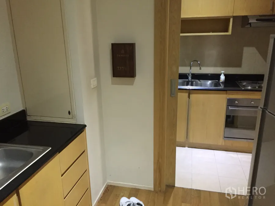 Condominium for rent in Watthana, Bangkok - Separate kitchen with black granite countertops, double sink and light wood cabinetry.