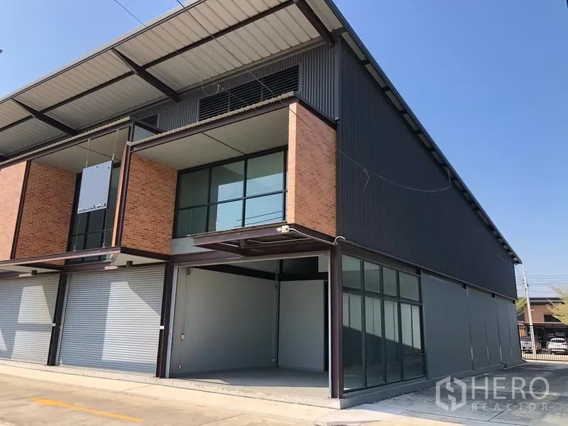 Warehouse for rent in Bang Phli, Samut Prakan - Modern two-storey warehouse exterior with brick and steel facade, glass mezzanine and covered loading bay.