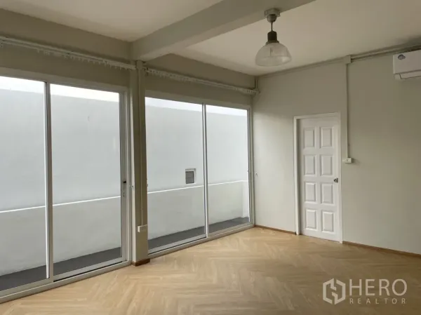 Detached House for rent or sale in Din Daeng, Bangkok - Bedroom with floor-to-ceiling sliders, wall air-conditioner and wood floors.