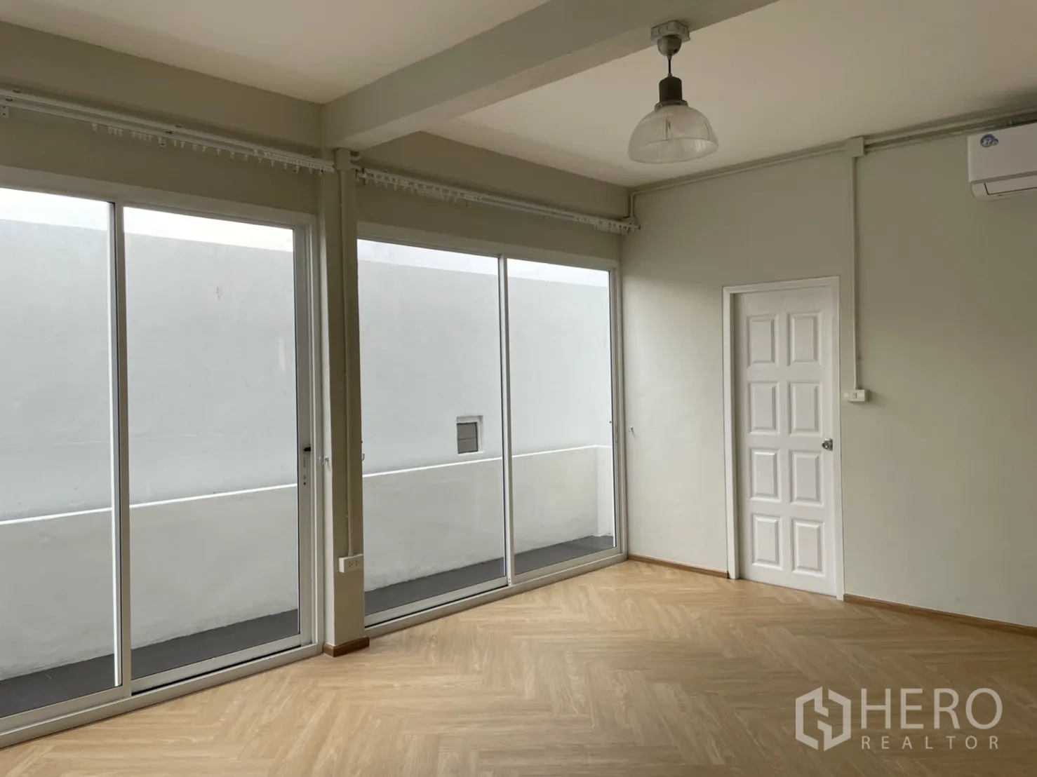 Detached House for rent or sale in Din Daeng, Bangkok - Bedroom with floor-to-ceiling sliders, wall air-conditioner and wood floors.