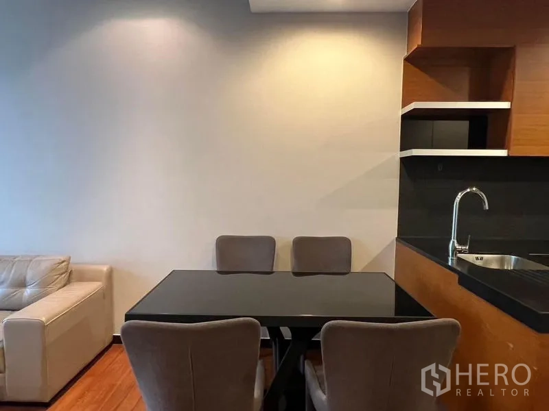 Condominium for rent - Dining nook with black glass table and four upholstered chairs beside the kitchen.
