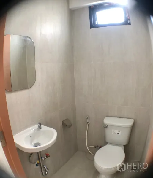 Home Office for rent in Phra Khanong, Bangkok - Compact bathroom with toilet, wall-hung basin and light ceramic tiles.