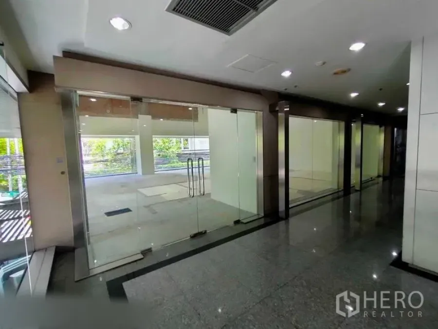 Retail Space for rent in Khlong Toei, Bangkok - Row of glass storefronts and lobby corridor outside the available retail unit.