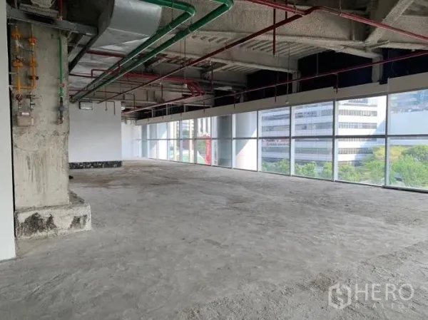 Retail Space for rent - Open-plan unit with city and tree views through full-height glass and visible MEP services.