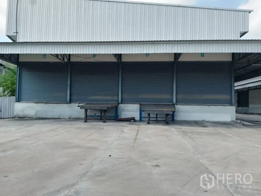 Warehouse for rent in Bang Phli, Samut Prakan - Exterior triple loading docks with closed roller shutters and dock levelers.
