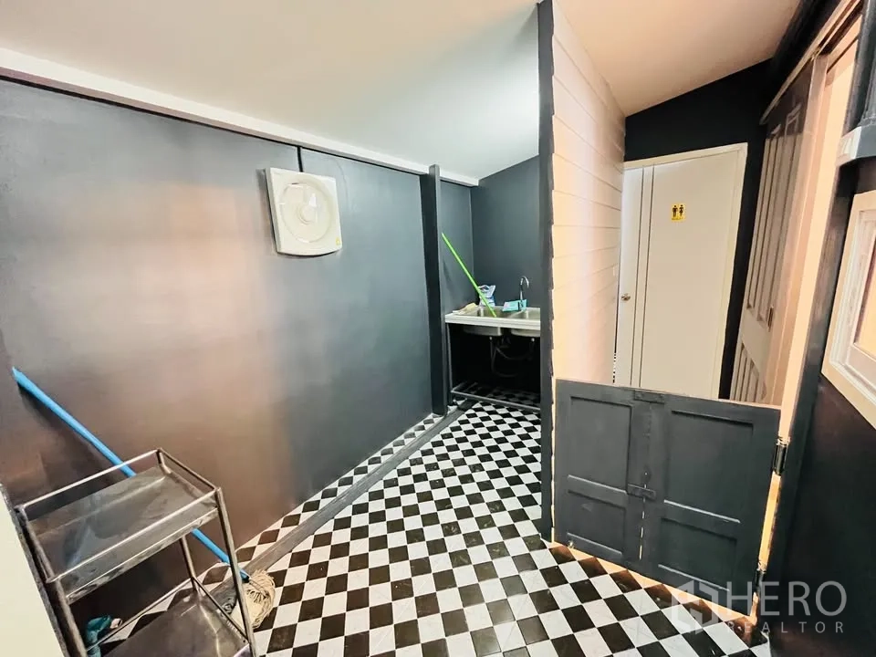 独立式住宅 出租 - 服务区设棋盘格地砖、水槽与储物柜，通往卫生间。