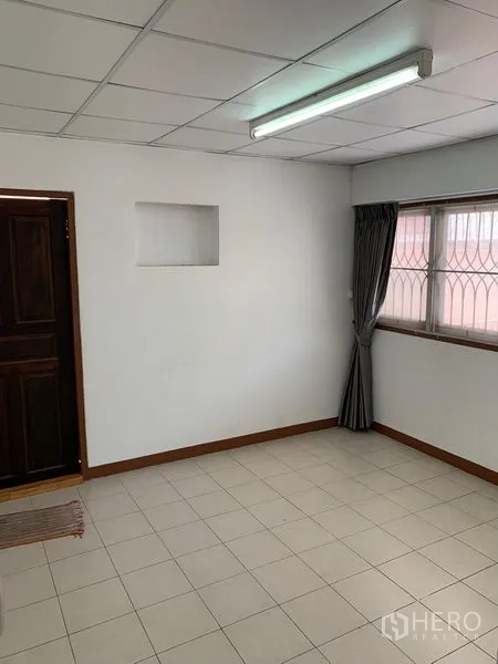 Office Space for rent in Chatuchak, Bangkok - Bright room with white tiled floor, curtained window with security grille and fluorescent light.