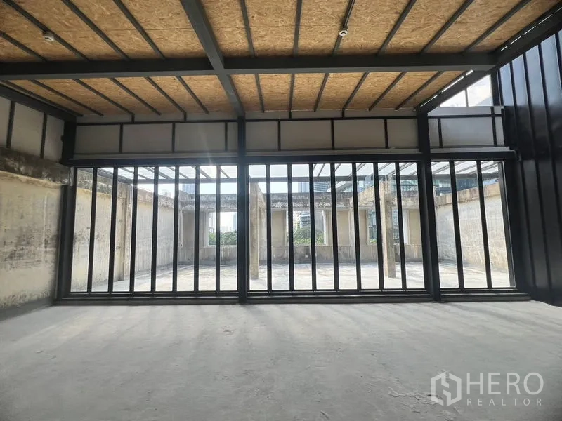 Retail Space for rent in Watthana, Bangkok - Full-width glass facade with vertical frames opening to a sunlit rooftop courtyard.