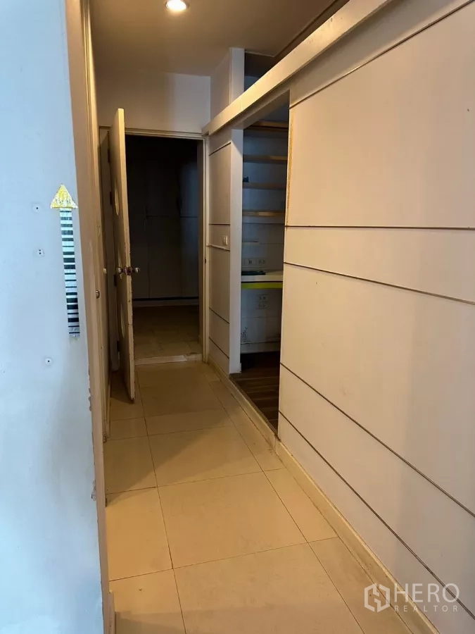 Shophouse for sale in Watthana, Bangkok - Narrow hallway with storage shelves and a door leading to rear rooms.