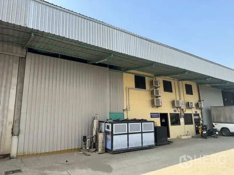 Factory for rent in Khlong Luang, Pathum Thani - Factory exterior in Khlong Luang with metal cladding, covered loading bay, HVAC units and parking area.