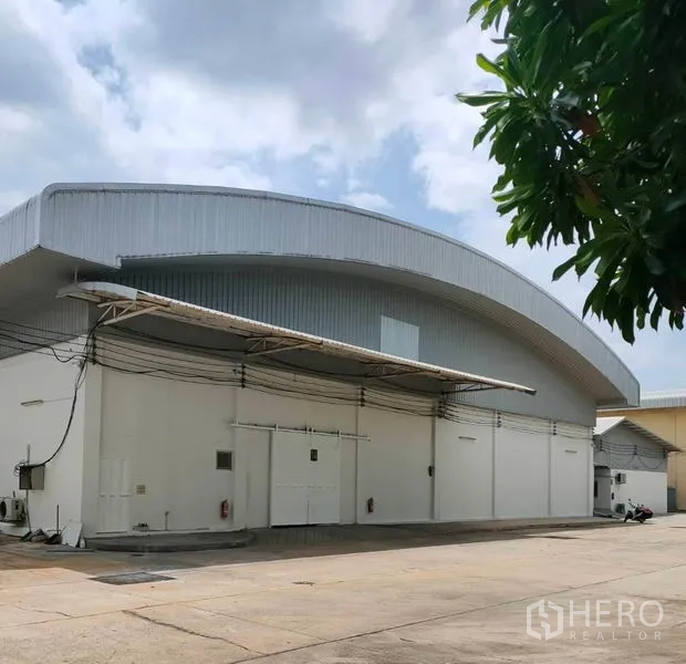 Warehouse for rent in Bang Pa-in, Phra Nakhon Si Ayutthaya - Modern white warehouse with arched metal roof, loading canopies and a wide concrete yard.