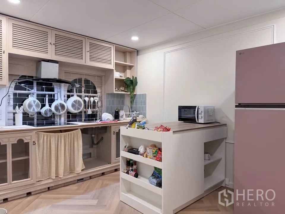 Detached House for rent in Huai Khwang, Bangkok - Practical kitchen with island, open shelving and hanging cookware.