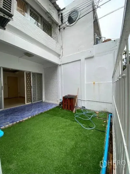 Townhouse for rent in Khlong Toei, Bangkok - Private yard with artificial grass and a blue-tiled terrace outside sliding glass doors.
