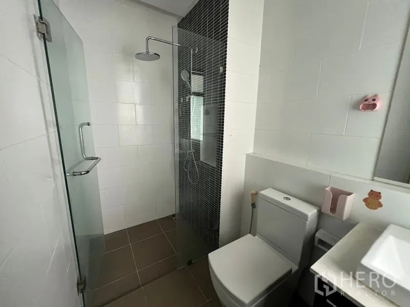 Townhouse for rent or sale in Khlong Toei, Bangkok - Modern bathroom featuring a frameless glass shower and white tiled walls.