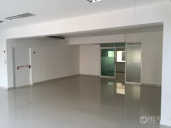 Office Space for rent in Bang Kapi, Bangkok - Spacious office floor featuring a glass-partitioned room and a fire-exit door.