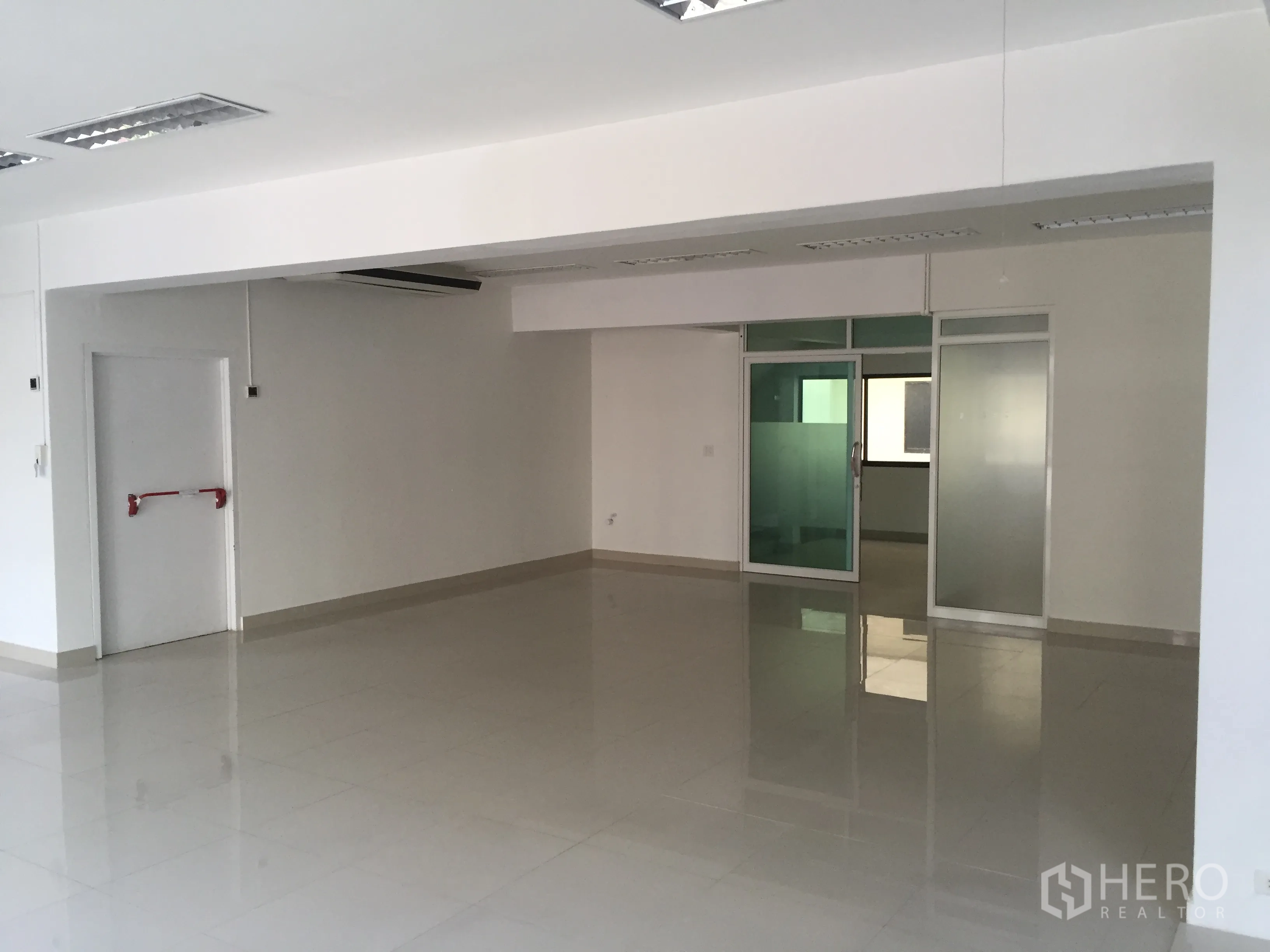 Office Space for rent in Bang Kapi, Bangkok - Spacious office floor featuring a glass-partitioned room and a fire-exit door.
