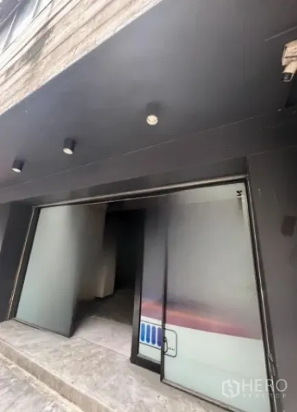 店屋 出租在Bang Rak, Bangkok - 一层入口，黑色雨棚下的推拉玻璃门与筒灯
