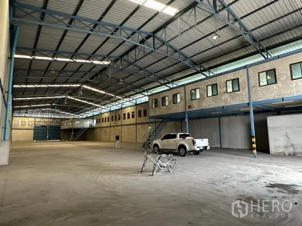 Warehouse for rent in Bang Phli, Samut Prakan - Open production and storage hall with mezzanine office rooms, pickup access, and bright roof lighting.